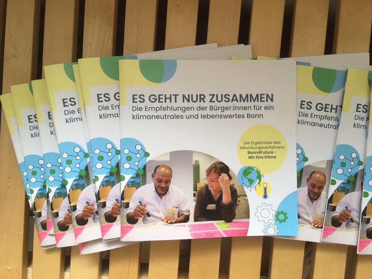 mehrere Exemplare der Mini-Broschüre zum Klima-Aktionsplan der Bürger:innen